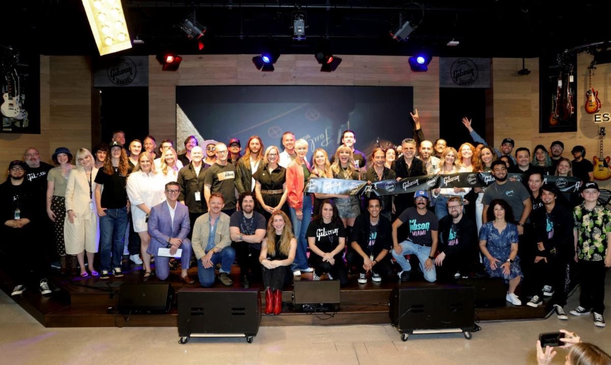 The full Gibson Garage Miami team and opening night artists celebrate together on stage.