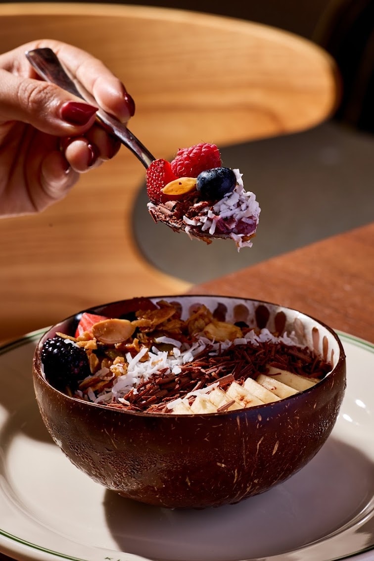 Grand Public açaí bowl served in a coconut shell with fresh berries, granola, and chocolate shavings