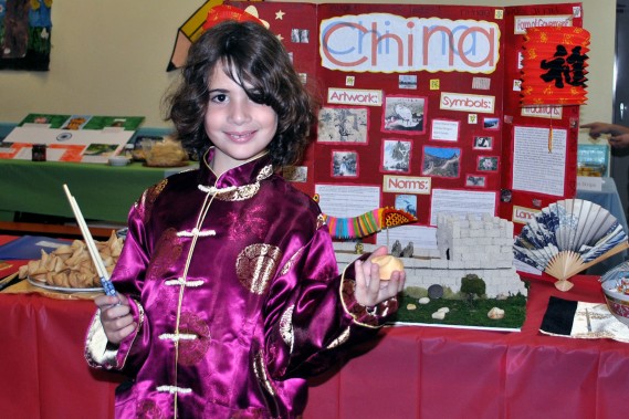 Photo Caption: Leo Fein, a second grade student in the Gordon Day School, is wearing traditional Chinese clothing and is standing in front of his elaborate display of China in honor of the school’s annual Culture Fair. 