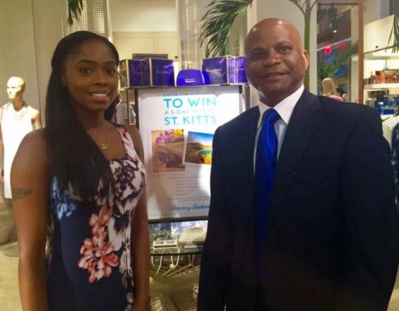 The Hon. Lindsay F.P. Grant, Minister of Tourism, International Trade, Industry and Commerce at the Tommy Bahama flagship store in New York City with a Tommy Bahama employee, in front of the 'Escape to St. Kitts' Sweepstakes in-store signage.