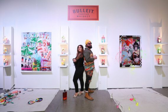 Artists Elidea and Jason Skeldon in front of limited-edition Bulleit Art in a Bottle Collection and accompanying canvases.