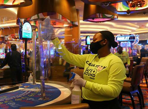  “Safe and Sound” Clean Team member Lounedie Philippe cleans and sanitizes Plexiglas partitions recently-installed on a table game at the reopened Seminole Hard Rock Hotel & Casino Hollywood.  (Courtesy Seminole Hard Rock Hotel & Casino Hollywood)