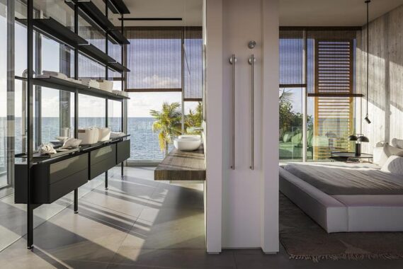 The owner’s primary suite is encased with sliding glass doors with views to the water, with metallic imprints of the board-formed concrete acting as a feature wall for the bed.Photo credit:
Kris Tamburello